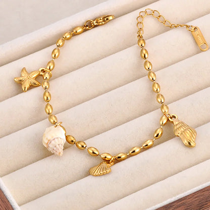 Bracelet doré à breloques avec coquillage