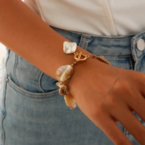 Bracelet bohème chic en nacre et métal doré, orné de breloques naturelles pour un style unique.