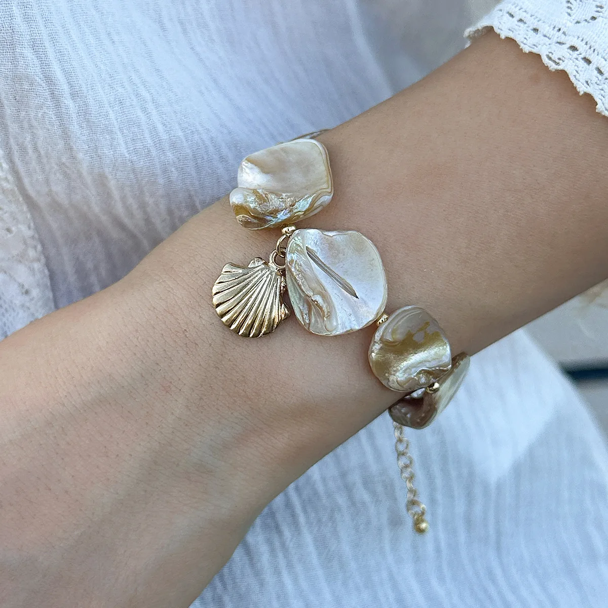 Bracelet bohème chic avec breloques en nacre et coquillage doré, parfait pour un look estival.