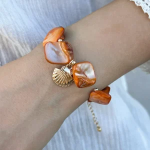 Bracelet bohème chic avec breloques en nacre orange et coquillage doré, parfait pour un look estival.