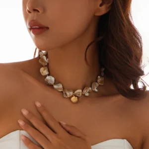 Collier breloque en nacre beige tissée, sublimant le décolleté avec élégance.