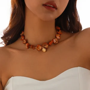 Collier breloque nacre orange tissée, style coq, sublimant le décolleté.