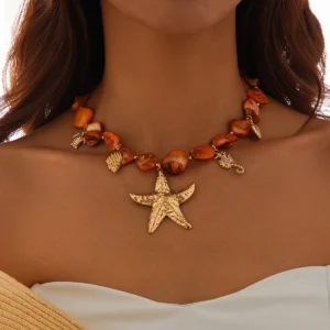 Collier breloque nacre orange tissée, orné d'une étoile de mer dorée et de coquillages pour un style marin chic.