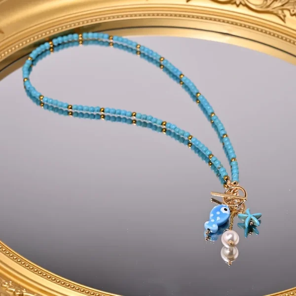 Collier perles bleues et breloques marines : poisson, étoile de mer, perle.