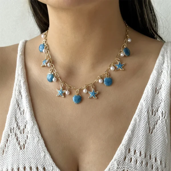 Collier ras-de-cou doré orné de breloques bleues en forme d'étoiles de mer et de perles, parfait pour un look estival.