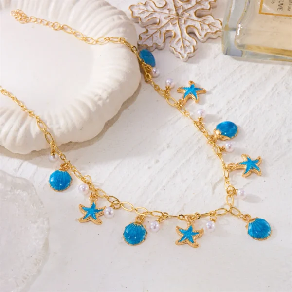 Collier ras-de-cou doré avec breloques étoiles de mer bleues et perles nacrées, style marin.