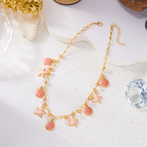 Collier ras-de-cou doré orné de breloques coquillages roses et étoiles de mer, perles nacrées, style marin chic.