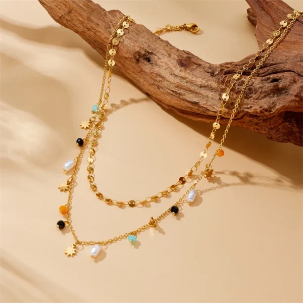Collier superposé doré avec breloques étoiles, perles blanches et colorées, style bohème chic.