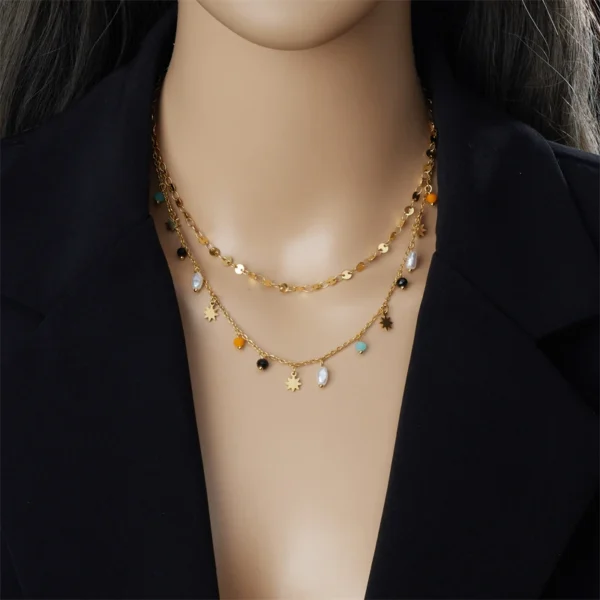 Collier superposé doré avec breloques colorées et perles, style bohème chic.